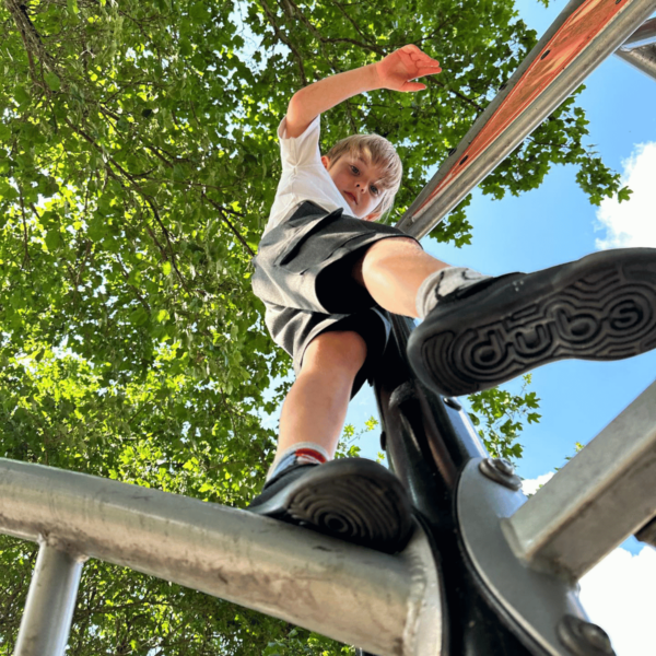 dubs childrens all black eco friendly trainers model image on climbing frame